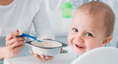 A mother feeding her baby with healthy food for a 9-month-old